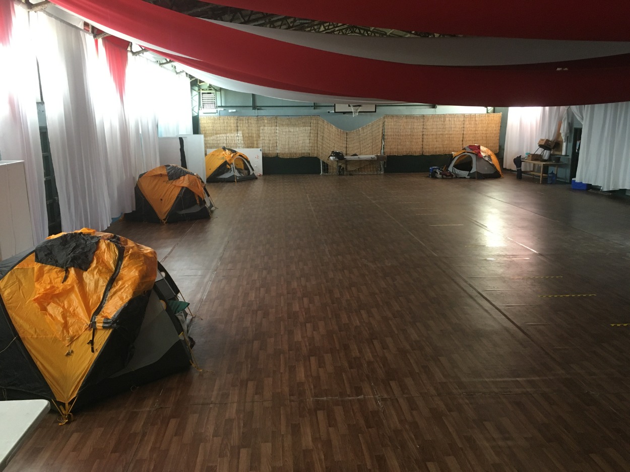 Small yellow tents pitched inside a community centre